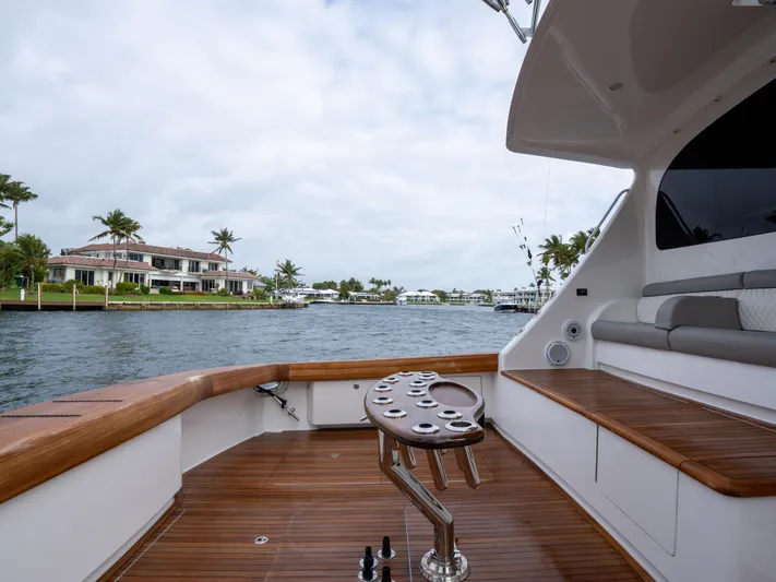 Reel Cents Yacht Photos Pics 2019 Viking 80 Enclosed Bridge yacht with wooden deck, overlooking waterfront homes and palm trees.