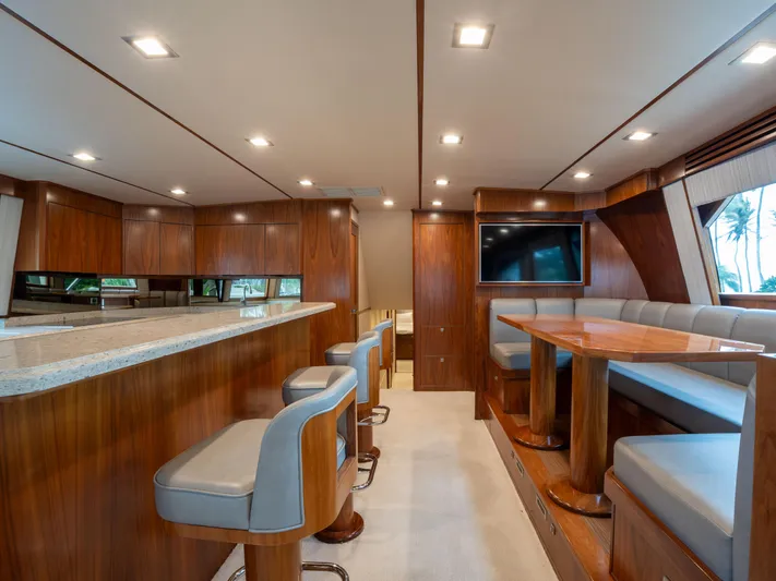 Reel Cents Yacht Photos Pics Luxurious interior of 2019 Viking 80 Enclosed Bridge yacht with modern seating and dining area.