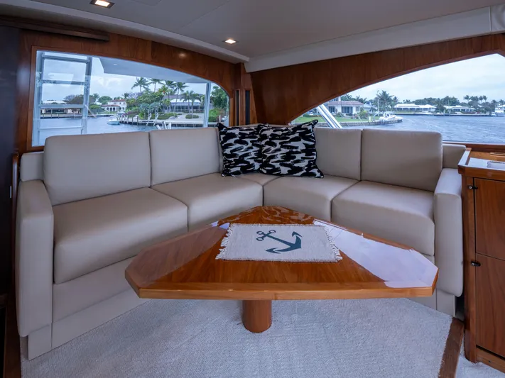 Reel Cents Yacht Photos Pics Luxurious interior of 2019 Viking 80 Enclosed Bridge yacht with elegant seating and wooden table.
