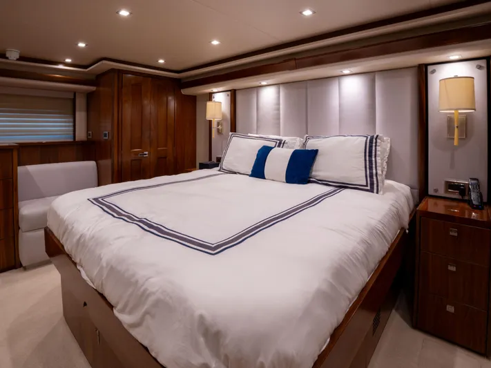 Reel Cents Yacht Photos Pics Luxurious bedroom interior of 2019 Viking 80 Enclosed Bridge yacht with elegant bedding and wood accents.