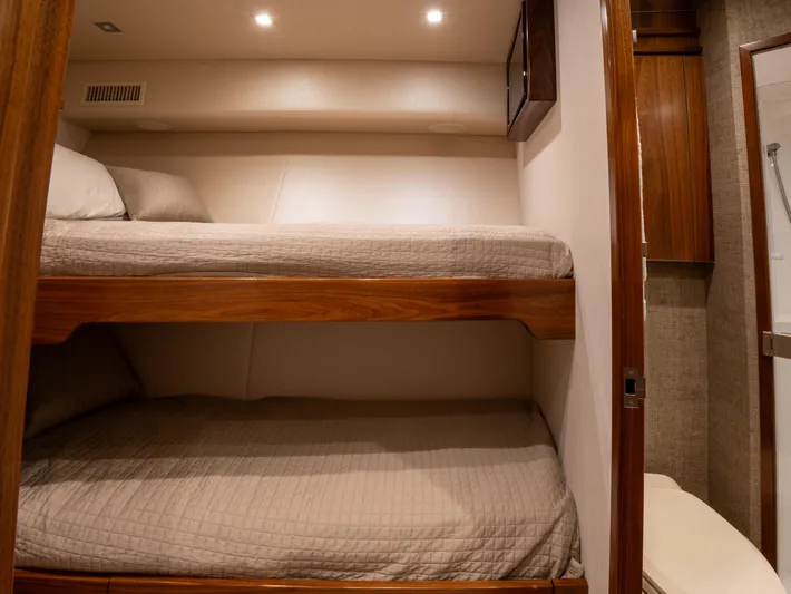 Reel Cents Yacht Photos Pics Bunk beds in 2019 Viking 80 Enclosed Bridge yacht cabin, featuring cozy bedding and warm lighting.