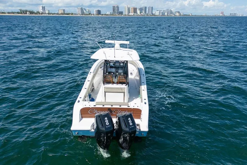 Change Clothes Yacht Photos Pics 2023 Sportsman Open 322 Center Console boat on ocean, city skyline in background.