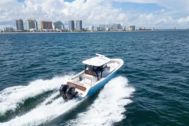 Change Clothes Yacht Photos Pics 2023 Sportsman Open 322 Center Console cruising near city skyline on ocean.