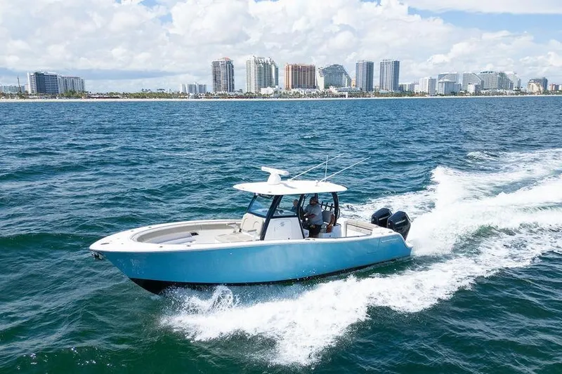 Change Clothes Yacht Photos Pics 2023 Sportsman Open 322 Center Console cruising near city skyline on blue ocean.