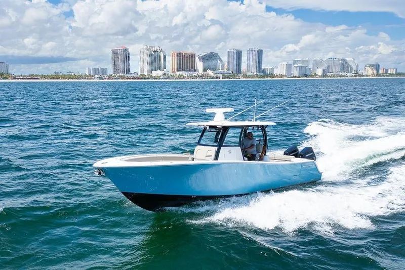 Change Clothes Yacht Photos Pics 2023 Sportsman Open 322 Center Console cruising on ocean with city skyline backdrop.