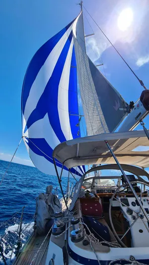 Surfing Safari Yacht Photos Pics 2010 Hallberg-Rassy 40 sailboat with blue and white spinnaker on open sea.