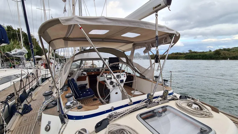 Surfing Safari Yacht Photos Pics Hallberg-Rassy 40 sailboat, 2010 model, docked by a calm river under cloudy skies.