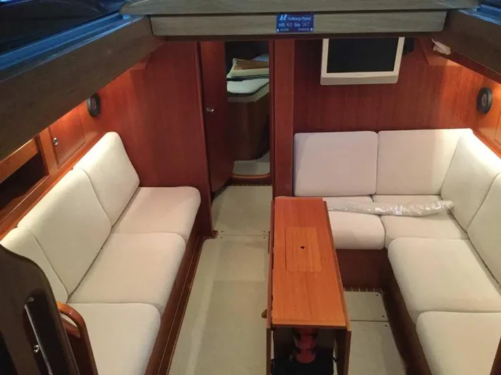 Surfing Safari Yacht Photos Pics Interior of 2010 Hallberg-Rassy 40 yacht with white seating and wooden table.