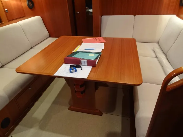 Surfing Safari Yacht Photos Pics Interior of 2010 Hallberg-Rassy 40 yacht with wooden table and cushioned seating.