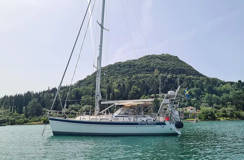 Surfing Safari Yacht Photos Pics Sailing yacht Hallberg-Rassy 40, 2010 model, anchored near lush green hills.