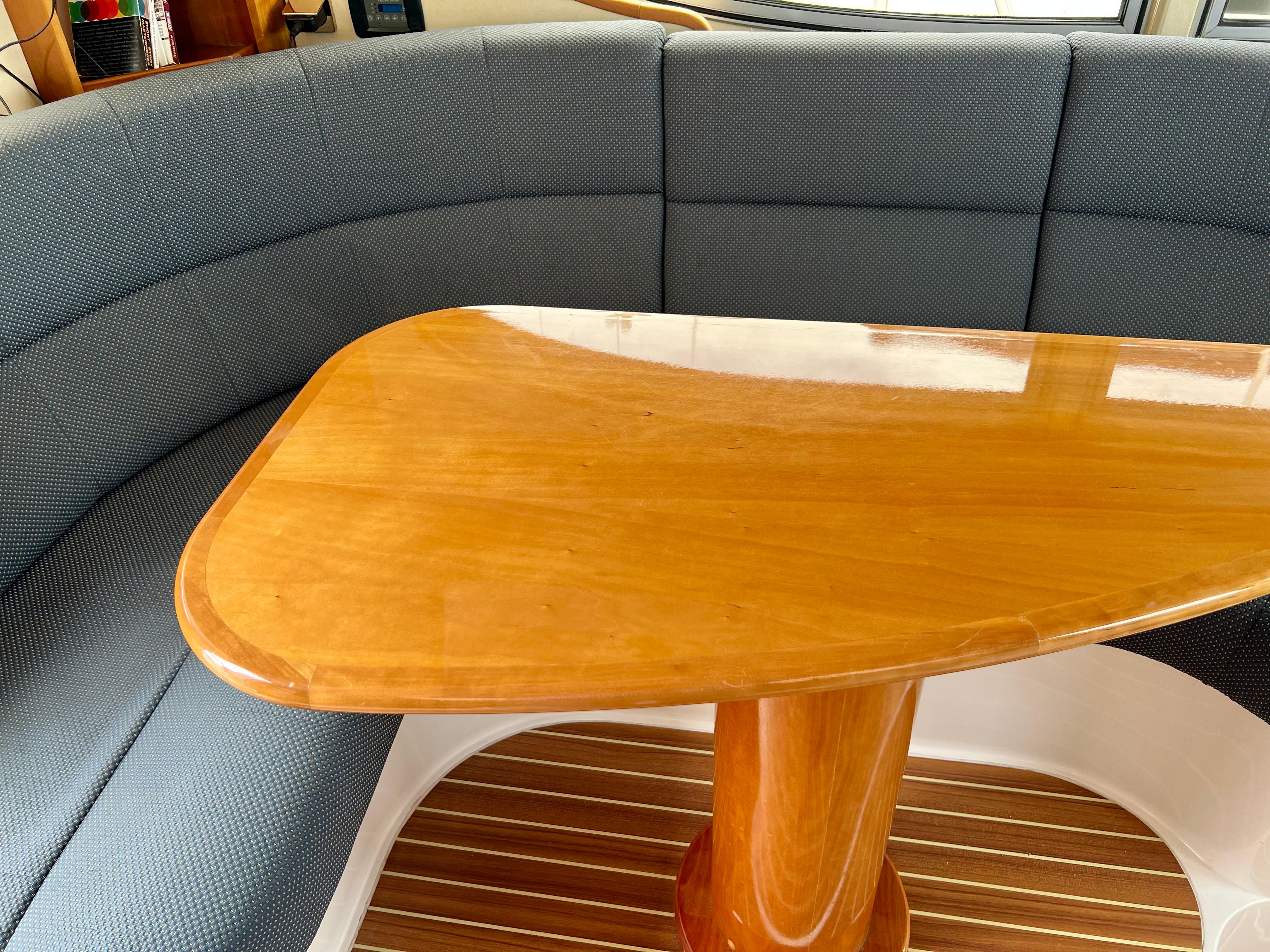 Luxurious interior of 2008 Elling E4 yacht with wooden table and cushioned seating.