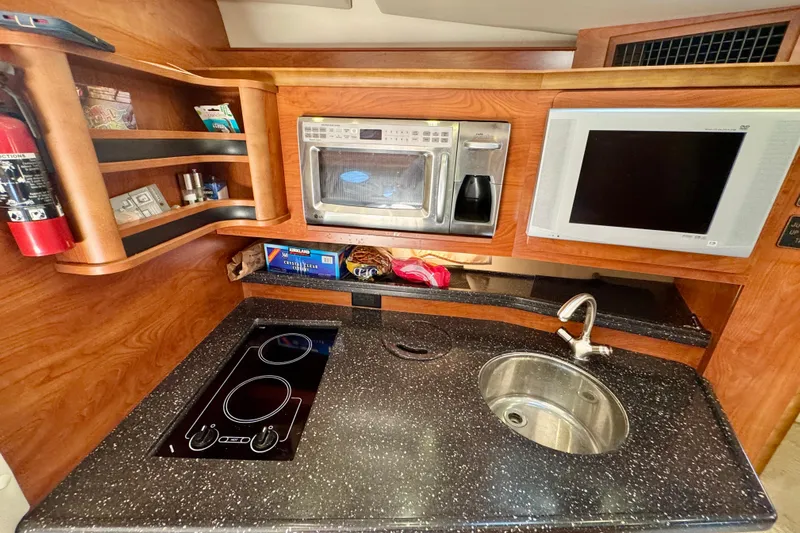 Escape Yacht Photos Pics 2009 Rinker 360 Express Cruiser kitchen with stove, sink, microwave, and TV.