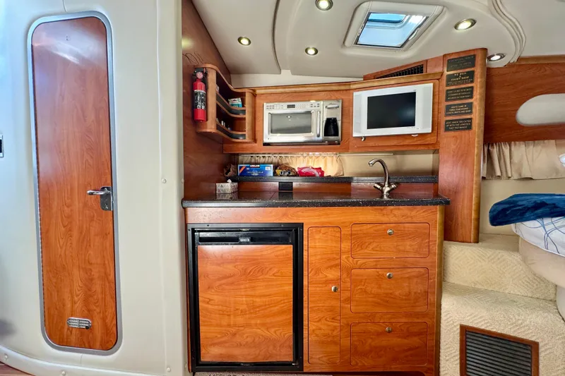 Escape Yacht Photos Pics 2009 Rinker 360 Express Cruiser interior with kitchenette, featuring wood cabinetry and modern appliances.