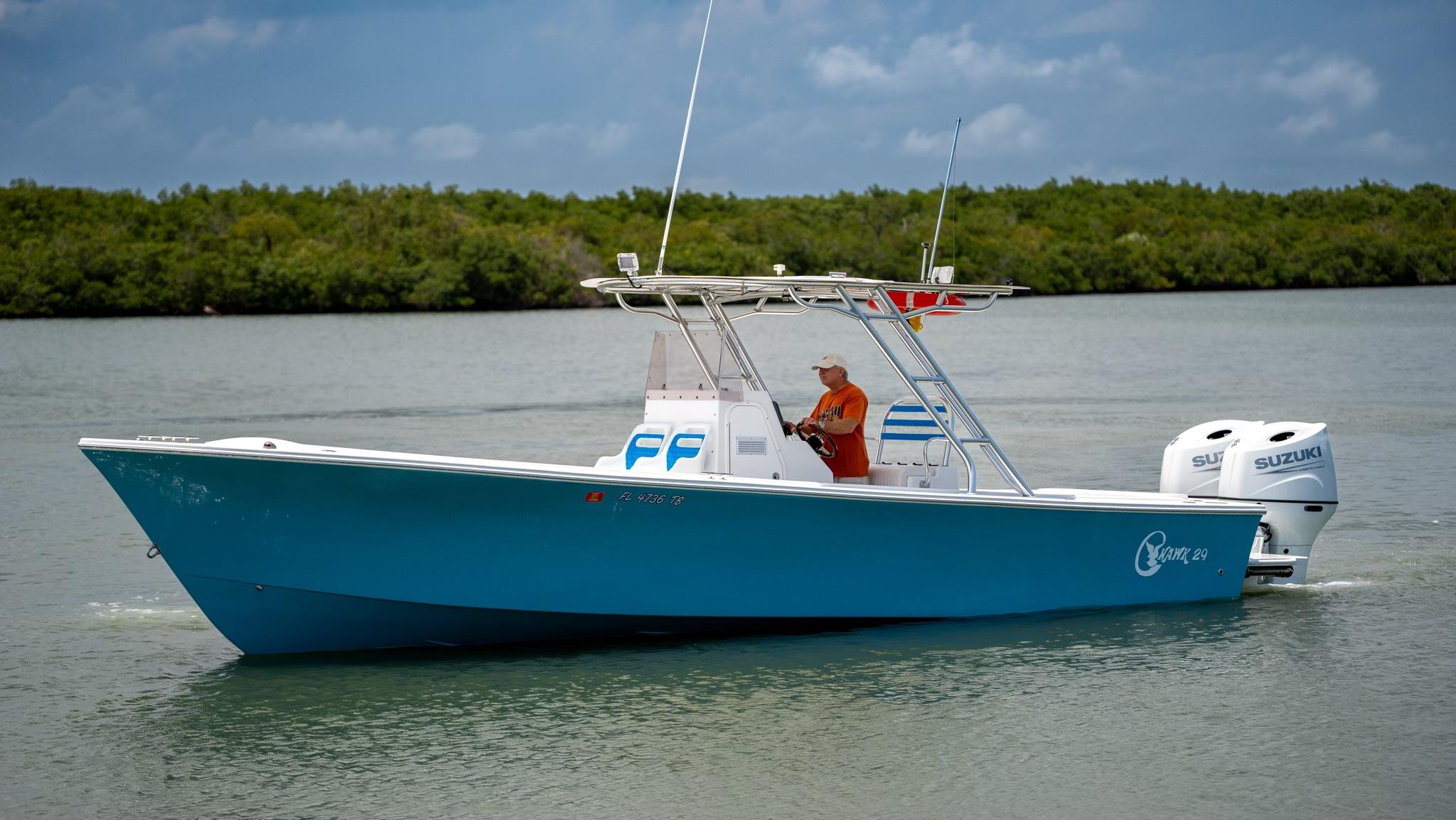 2021 C-Hawk 29CC boat cruising on a calm river with lush greenery.