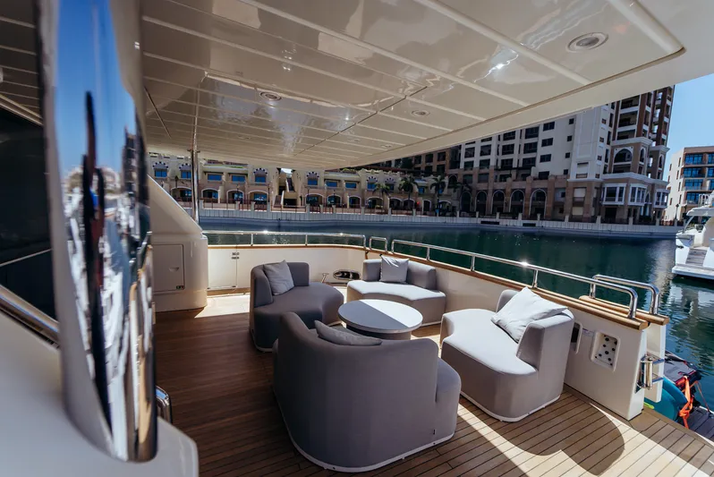Apache Yacht Photos Pics Luxurious Falcon 86 yacht deck with modern seating, overlooking marina and waterfront buildings.