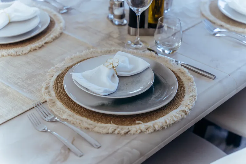 Apache Yacht Photos Pics Elegant table setting with white napkin, silverware, and glassware on a fringed placemat.