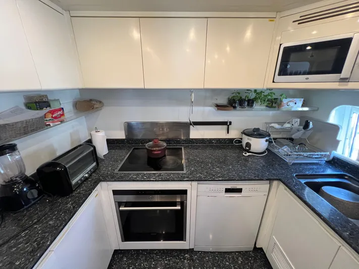 Apache Yacht Photos Pics Modern kitchen with appliances, white cabinets, and granite countertops in a Falcon 86 yacht, 2004 model.