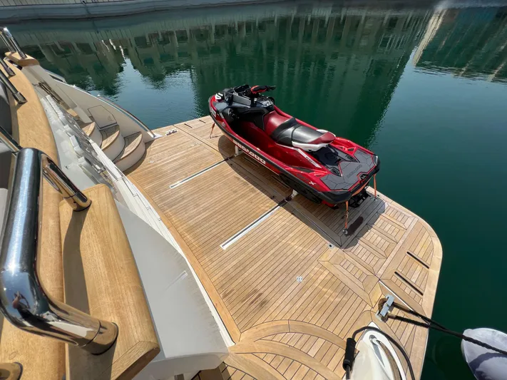 Apache Yacht Photos Pics Luxury yacht Falcon 86 (2004) with red jet ski on wooden deck, docked in calm waters.
