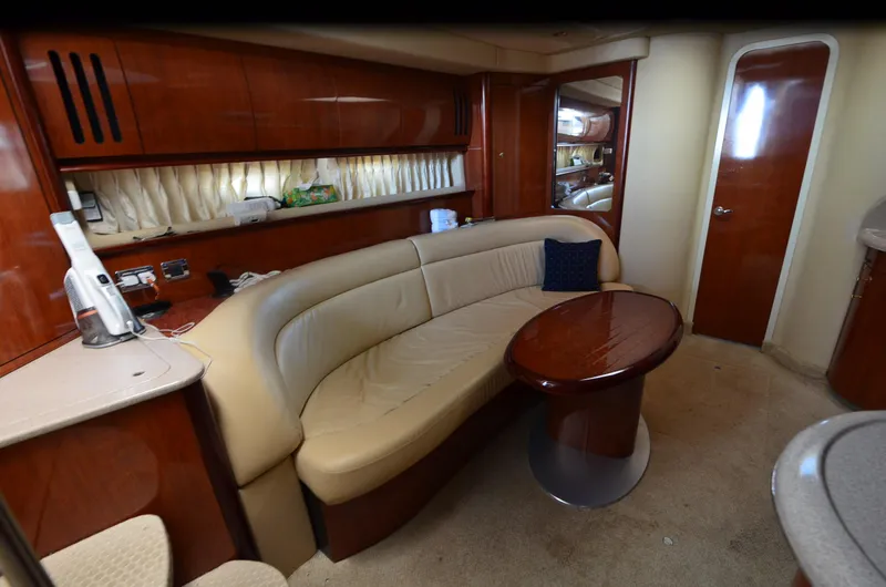Rehab Is For Quitters Yacht Photos Pics Interior of 2003 Sea Ray 420 Sundancer yacht with beige seating and wooden table.
