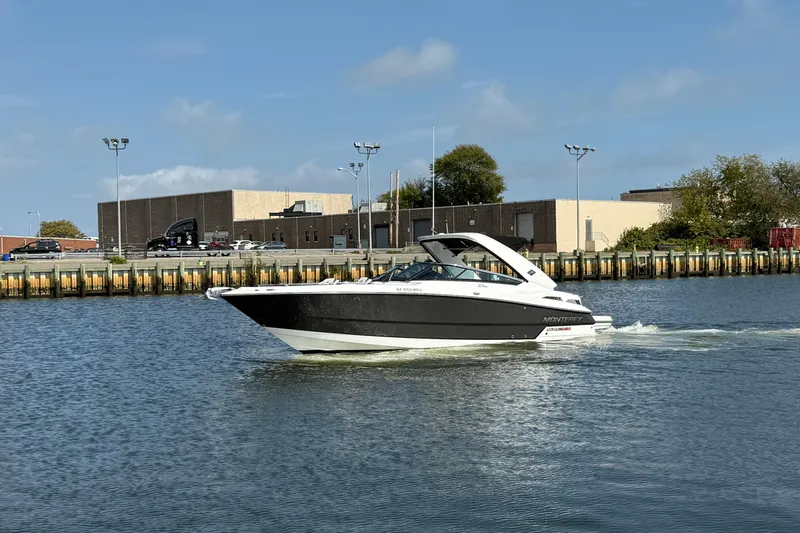  Yacht Photos Pics 2018 Monterey 328SS Super Sport boat cruising on a calm waterway near industrial buildings.