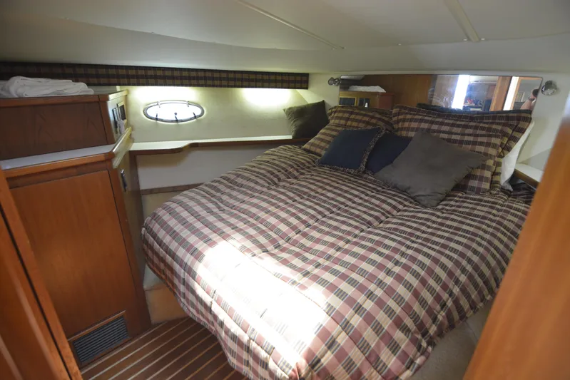 Uncouth Yacht Photos Pics Cozy bedroom in a 2000 Tiara Yachts 4100 Open with plaid bedding and wooden cabinetry.