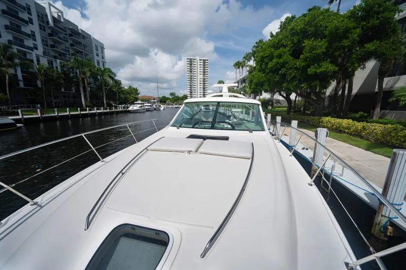  Yacht Photos Pics 2006 Sea Ray 48 Sundancer yacht docked by waterfront buildings and lush greenery.