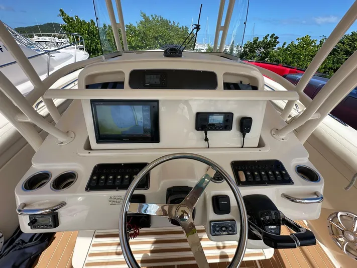  Yacht Photos Pics 2018 Grady-White Canyon 336 helm with navigation screens and controls, surrounded by lush greenery.