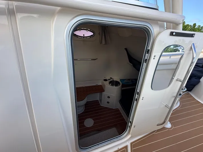  Yacht Photos Pics 2018 Grady-White Canyon 336 boat cabin interior with compact bathroom and wooden flooring.