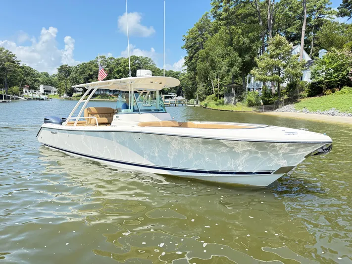 My Ginny Yacht Photos Pics 2014 Pursuit ST 310 Sport boat on a sunny day, near a lush shoreline.