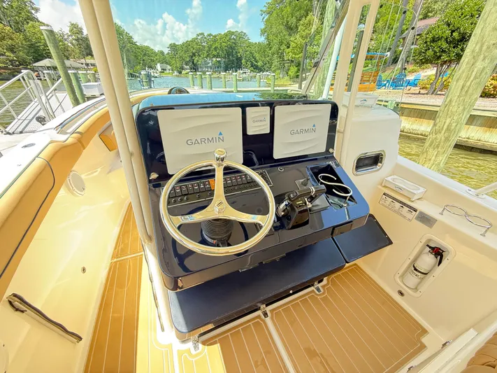 My Ginny Yacht Photos Pics 2014 Pursuit ST 310 Sport boat helm with Garmin navigation, docked by a scenic waterfront.