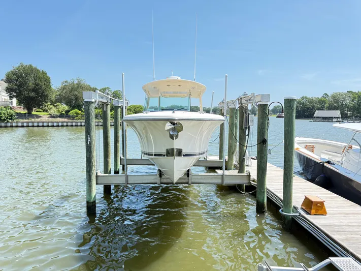 My Ginny Yacht Photos Pics 2014 Pursuit ST 310 Sport boat docked on a lift by the water.