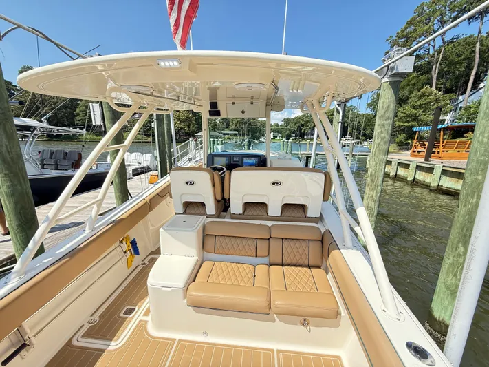 My Ginny Yacht Photos Pics 2014 Pursuit ST 310 Sport boat interior with tan seating and helm, docked at marina.