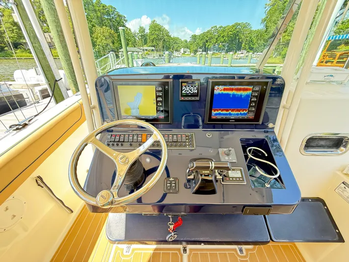 My Ginny Yacht Photos Pics Control panel of a 2014 Pursuit ST 310 Sport boat with navigation screens and steering wheel.