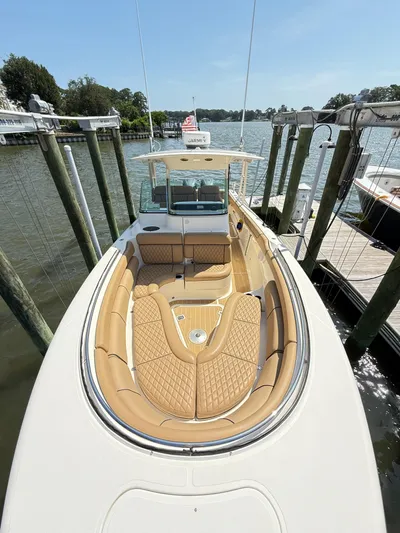 My Ginny Yacht Photos Pics 2014 Pursuit ST 310 Sport boat with tan seating, docked by a scenic waterfront.