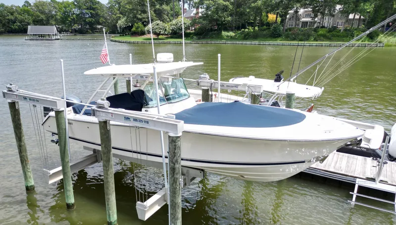 My Ginny Yacht Photos Pics 2014 Pursuit ST 310 Sport boat docked on a lift by a serene lake.