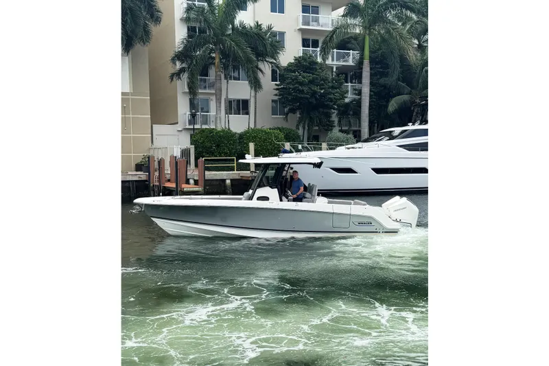  Yacht Photos Pics 2024 Boston Whaler 280 Outrage cruising near waterfront buildings and palm trees.