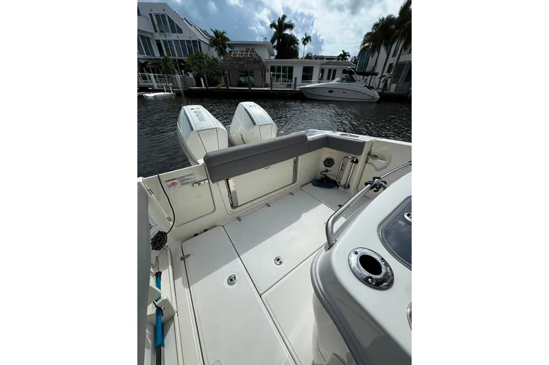  Yacht Photos Pics 2024 Boston Whaler 280 Outrage boat deck with dual engines, docked by waterfront homes.