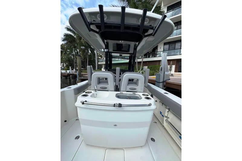  Yacht Photos Pics 2024 Boston Whaler 280 Outrage boat interior with seating and console, docked near palm trees.