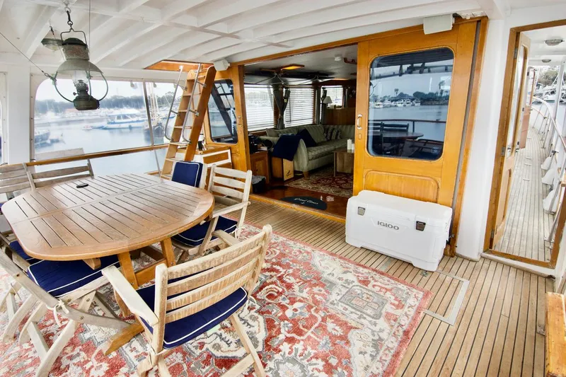 Grand Times Yacht Photos Pics 1969 Grand Banks Classic yacht interior with wooden dining set, nautical decor, and scenic marina view.