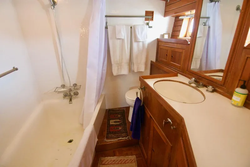 Grand Times Yacht Photos Pics Bathroom interior of a 1969 Grand Banks Classic yacht with wooden cabinetry and bathtub.