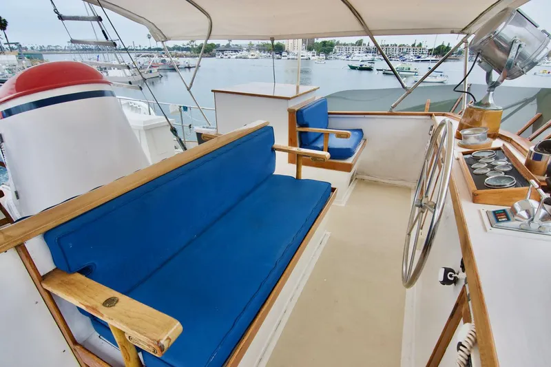 Grand Times Yacht Photos Pics 1969 Grand Banks Classic yacht deck with blue seating and steering wheel, overlooking marina.