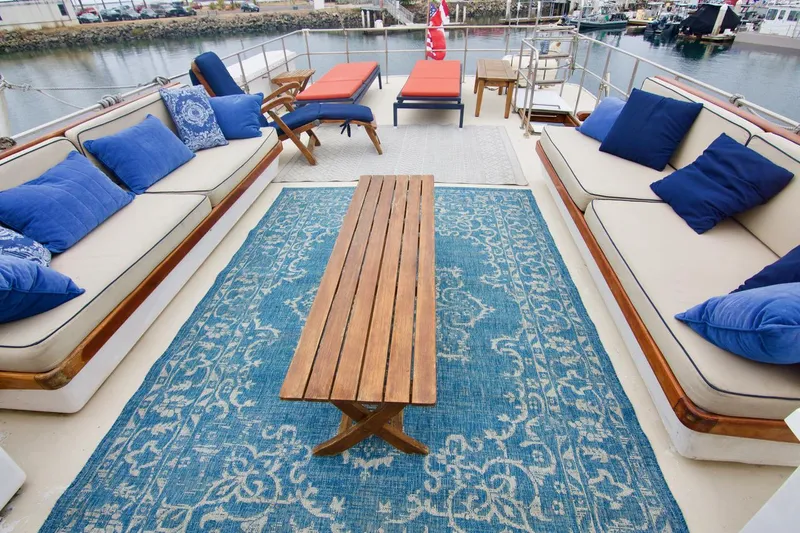 Grand Times Yacht Photos Pics 1969 Grand Banks Classic yacht deck with blue cushions, wooden table, and patterned rug.
