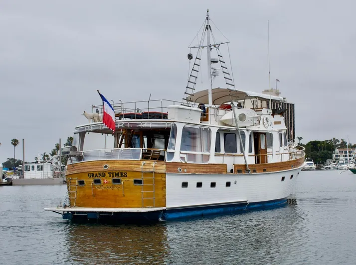 Grand Times Yacht Photos Pics 1969 Grand Banks Classic yacht on water, featuring wooden details and a flag at the stern.