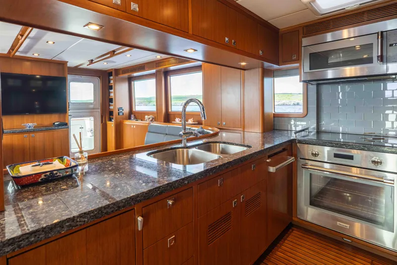 Martini Yacht Photos Pics Luxurious kitchen interior of 2022 Nordhavn N63 yacht with modern appliances and wood finishes.