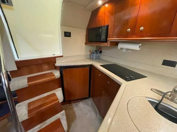  Yacht Photos Pics 2006 Cruisers Yachts 340 Express interior kitchen with wood cabinetry and modern appliances.