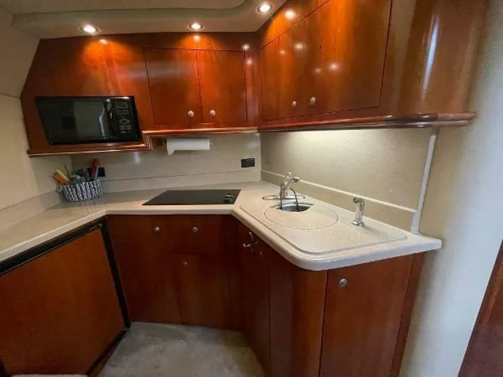  Yacht Photos Pics 2006 Cruisers Yachts 340 Express kitchen with wood cabinets, sink, and microwave.