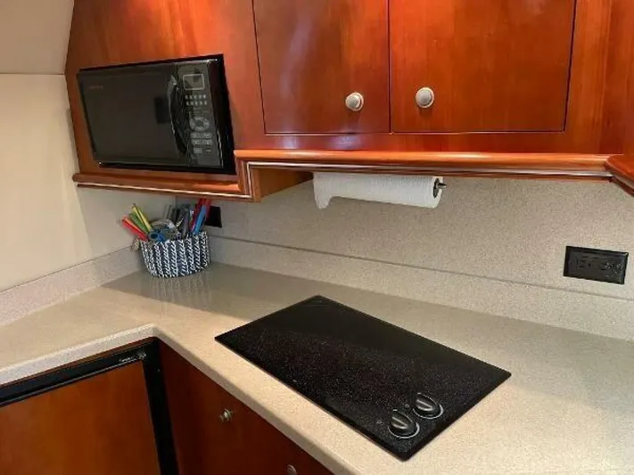 Yacht Photos Pics 2006 Cruisers Yachts 340 Express kitchen with microwave, stovetop, and wooden cabinets.
