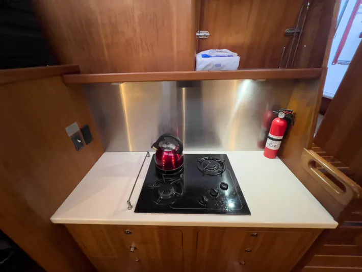 Whatabout Yacht Photos Pics Compact kitchen area in a 2005 Antares PDQ 44 yacht with stove and fire extinguisher.