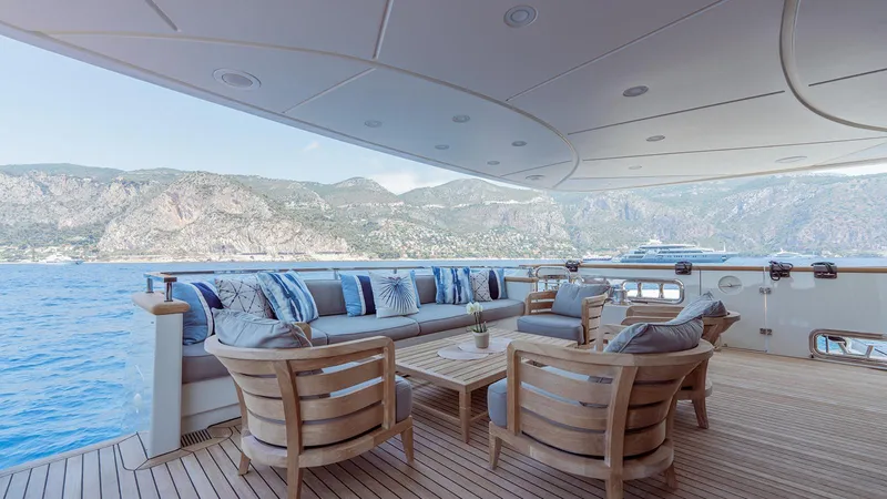 Away Yacht Photos Pics Luxurious Sanlorenzo SD125 yacht deck with elegant seating, overlooking scenic coastal mountains.