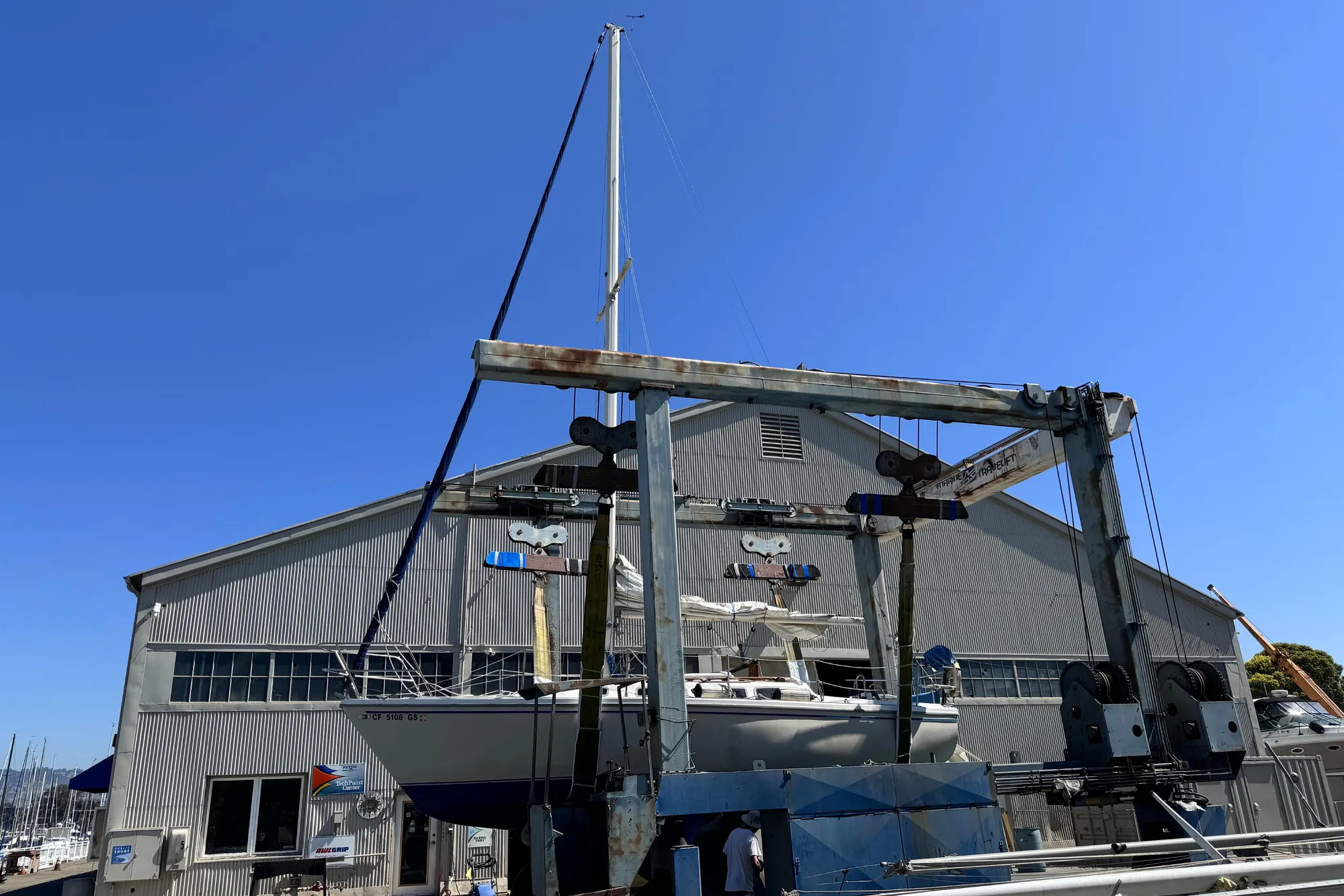 1980 Catalina 30 sailboat in dry dock, marina background, clear blue sky.
